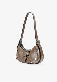 Bolso de hombro de imitación cuero marrón con forma curved, tachuelas plateadas y una correa ancha ajustable, que presenta un detalle de hebilla.