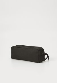 Trousse en tissu noir de forme rectangulaire, dotée d'une fermeture éclair et d'une petite languette sur le côté pour une ouverture facile.