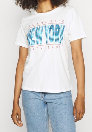 Person wearing white T-shirt with blue striped "NEW YORK" text and red "AUTHENTIC CITY - 1987" print, paired with light blue denim jeans.