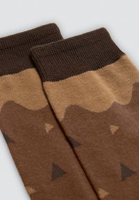 Calcetines marrones con un patrón y un puño acanalado en marrón más oscuro, que presentan un diseño de olas y pequeñas formas triangulares en tonos de marrón.