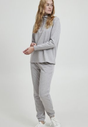 Hellgrauer Sweatshirt und Jogginghose aus weichem Stoff. Das Oberteil hat einen halben Reißverschlusskragen, und die Hose hat elastische Bündchen.