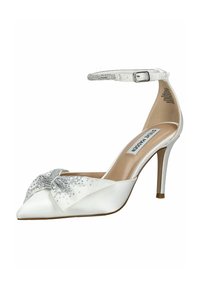 Scarpa bianca con tacco alto, punta affusolata, finitura in raso, un fiocco adornato con strass e una cinghia alla caviglia con dettagli in fibbia.