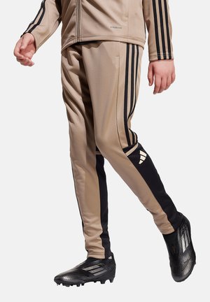 Beige sportbroek met zwarte zijkanten en een Adidas-logo, gemaakt van gladde stof, heeft een slim fit ontwerp en taps toelopende benen.