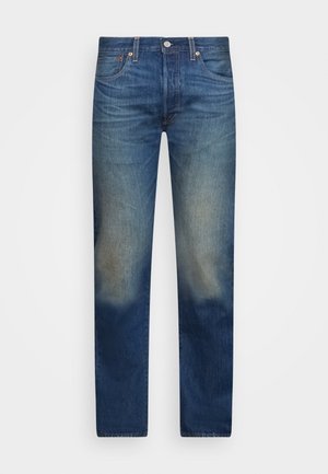 Jean en denim bleu avec des zones délavées sur les cuisses et les genoux, doté de poches avant et de passants pour ceinture.