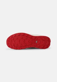 Soletta in gomma con un motivo di battistrada profondo in rosso e superficie texture, progettata per trazione e aderenza. Presenta una parte superiore beige.