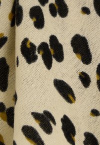 Tela con estampado de leopardo que presenta un fondo beige con manchas negras y amarillas, tejido texturizado. El patrón varía en tamaño y forma.