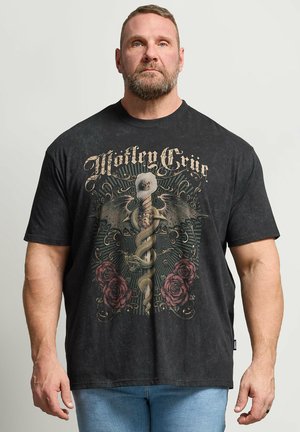 Muscular man wearing black Mötley Crüe t-shirt with snake entwined around winged staff and red roses, standing against plain background.