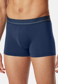 Pantaloni boxer blu navy realizzati in un tessuto liscio ed elastico con una vita ampia che presenta un logo di marca e dettagli a strisce in contrasto.