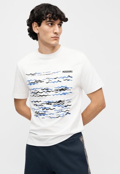 Λευκό βαμβακερό μπλουζάκι με κυματιστό σχέδιο σε μπλε και μαύρο. Λογότυπο "MISSONI" τυπωμένο μαύρο στην επάνω αριστερή πλευρά. Κοντά μανίκια.