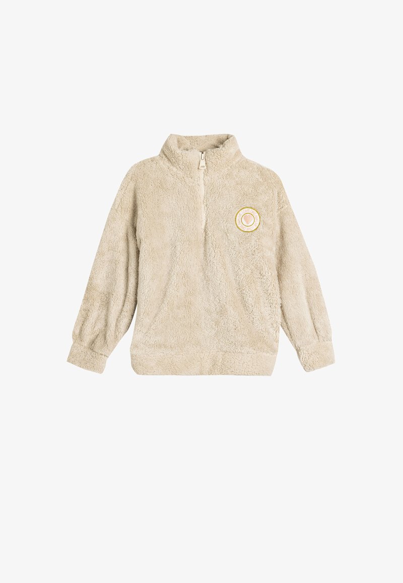 Beiger Fleece-Pullover mit Viertelreißverschluss, langen Ärmeln und einem runden Aufnäher mit einem Herzdesign in Gold und Weiß auf der Brust.