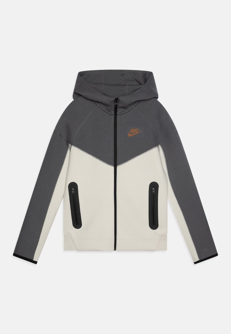 Grauer und cremefarbener Kapuzenpullover mit durchgehendem Reißverschluss, der ein dreieckiges Farbkombinationsdesign und zwei seitliche Reißverschlusstaschen aufweist. Nike-Logo in Orange.