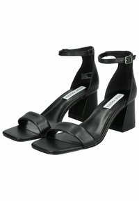 Le scarpe sandali nero in pelle con tacco quadrato presentano una punta squadrata, una cinghia alla caviglia con fibbia e una suola piatta per un aspetto moderno e minimalista.