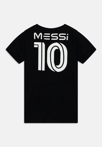 Fekete pamut póló, amelyen nagy fehér nyomtatott "MESSi" név és a hátoldalon a "10" szám található, klasszikus kerek nyakkivágással és rövid ujjal.