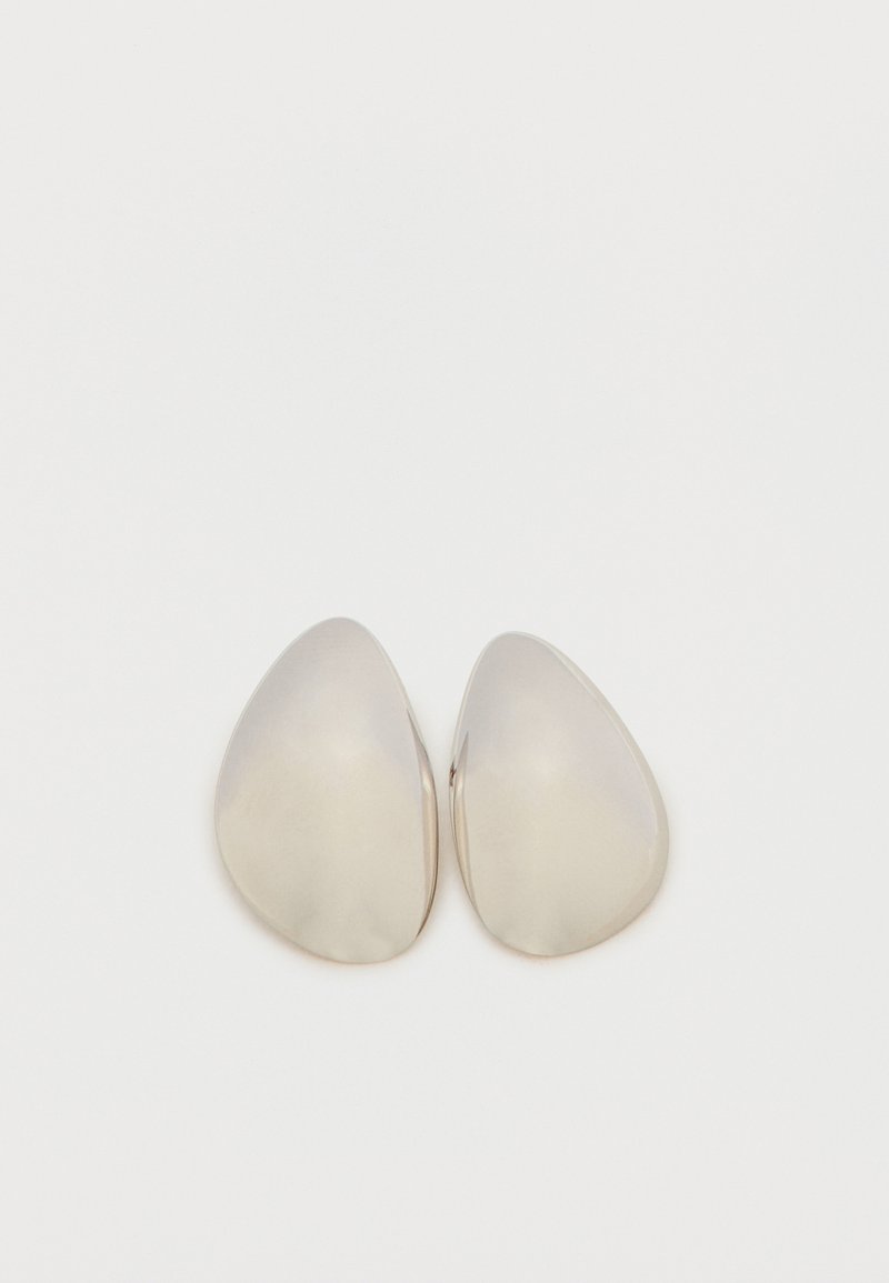 Pár sima, ezüst, aszimmetrikus csepp alakú fülbevaló tükröződő fémes felülettel, fehér háttéren.