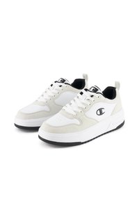 Białe sneakersy z zamszowymi akcentami, okrągłym noskiem, sznurowanym zapięciem i czarną gumową podeszwą. Posiadają logo po boku i czarną pętelkę przy pięcie.