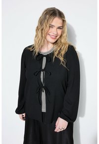 Blusa nera texturizzata con maniche lunghe, dotata di tre nastri decorativi sul davanti, sopra uno strato interno a righe.