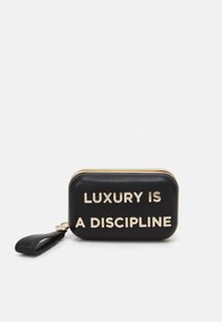 Czarna skórzana prostokątna kopertówka z złotym napisem "LUKSUS TO DYSCYPLINA." Posiada zamek błyskawiczny i pasek na nadgarstek. Gładka tekstura.