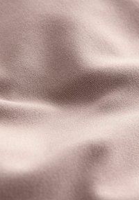 Tissu doux rose clair avec une texture lisse, présentant des variations subtiles de teinte et un tissage fin et régulier, créant des plis doux et fluides.