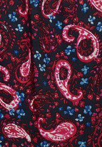 Mörk tyg med ett paisleymönster i röd och rosa, med små blå och vita blommor som accentuerar, vilket skapar en texturerad visuell design.