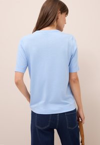 Hellblaues Kurzarm-T-Shirt, weicher Stoff, lockere Passform, runder Ausschnitt, kombiniert mit dunklen Jeans, schlichtes Design ohne sichtbare Muster.