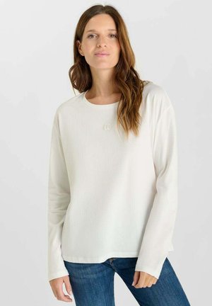Witte lange mouwen shirt van lichtgewicht stof, met een ronde hals, een losse fit en een subtiele logodetail op de borst. Draagt met blauwe jeans.