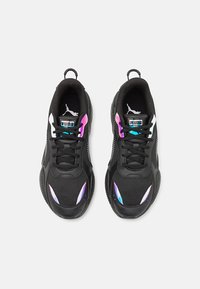 Ein Paar schwarze Puma-Sneaker mit schwarzen Schnürsenkeln, weißen Logos und irideszenten lila und blauen Akzenten auf einem weißen Hintergrund.