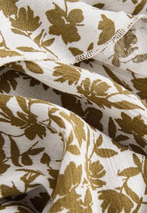 Tkanina s cvjetnim uzorkom u krem i maslinasto zelenoj boji, koja ima mekan, teksturirani tkanje s razdrapanim rubovima i isprepletenim listovima i cvjetovima.