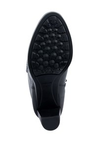 Zapato de cuero negro con una suela de goma texturizada que presenta clavos redondeados para mayor agarre. El tacón es ligeramente redondeado, y el diseño es elegante y moderno.