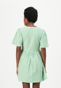 Vestido de manga curta em verde e branco com riscas verticais, ajustado na cintura com uma saia franzida. Tecido leve com uma textura subtil.