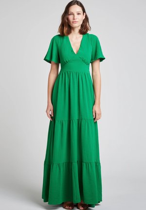Robe maxi verte en tissu texturé. Caractéristiques des manches courtes en volants, un décolleté en V profond et des volants superposés au bas.
