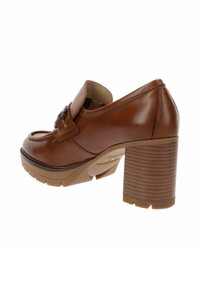 Mocasin de piel marrón con tacón grueso apilado y hebilla decorativa en la parte superior, vista lateral sobre fondo blanco.