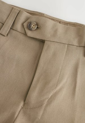 Pantalons beiges à plat, avec une fermeture à bouton et des passants de ceinture. Le tissu a une texture lisse avec des coutures propres et ajustées.