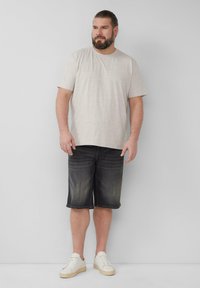 Lichtbeige t-shirt met korte mouwen, gecombineerd met donkere denim shorts, gedragen met witte sneakers. Eenvoudig ontwerp, zachte textuur, casual pasvorm.