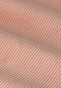 Textiel met een zachte roze kleur en subtiele golvende ribbels, lichtgewicht en glad. Een opvallend lijnpatroon voegt dimensie en interesse toe.