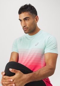 Herre trening t-skjorte i mintgrønn med korallgradient. Har korte ermer, rund hals og subtile mønstre på stoffet.