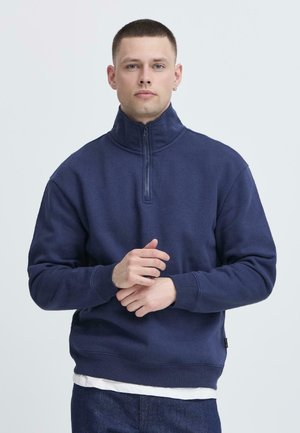 Navy zip-up sweatshirt with a high collar, ribbed cuffs, and hem; cotton-blend material, featuring a soft texture and relaxed fit.