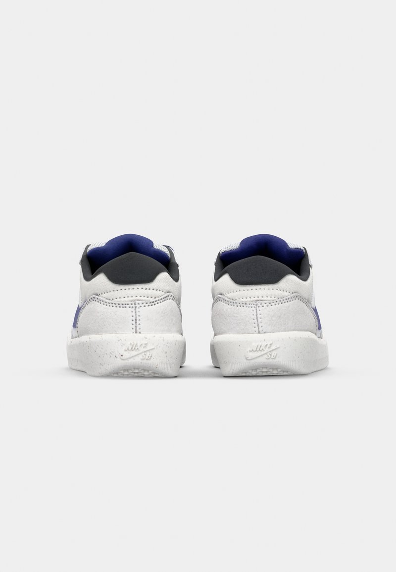 Weiße Sneaker mit grauen und blauen Akzenten. Weiches Wildledermaterial, runde Form, strukturiertes Hinterteil und auffälliges Logo auf der Sohle.