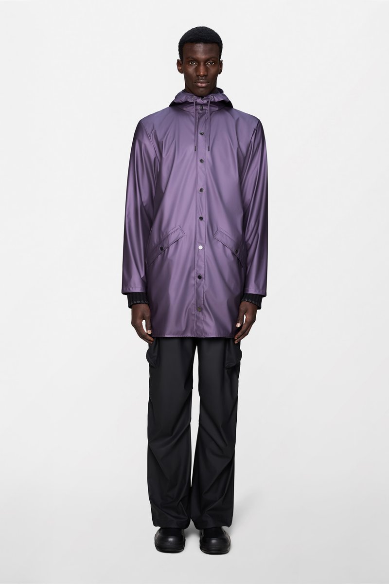 Μωβ αδιάβροχο παλτό με κουκούλα, κουμπιά με τσιμπίδα και πλαϊνές τσέπες, που φοριέται πάνω από μαύρο παντελόνι και μπότες. Λείο, γυαλιστερό υλικό.