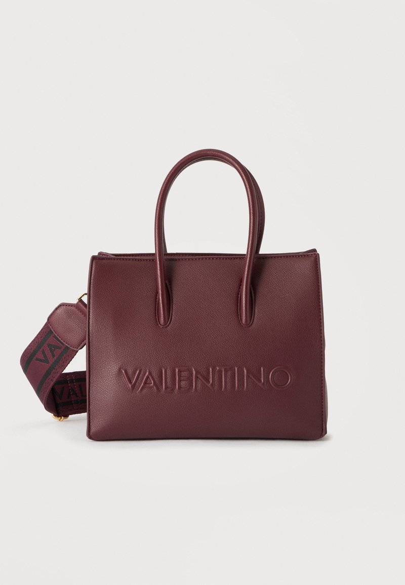 Τσάντα tote από δέρμα burgundy με δύο λαβές, ανάγλυφο λογότυπο "VALENTINO" και ρυθμιζόμενο ιμάντα ώμου με λογότυπο σε λευκό φόντο.