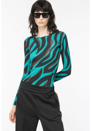 Top a maniche lunghe in turchese e nero con motivo a strisce zebrate, abbinato a pantaloni neri con tasche laterali e vita elasticizzata.