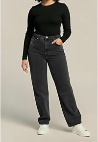 Top negro ajustado de manga larga combinado con jeans de mezclilla gris oscuro, de tiro alto y ajuste holgado. La modelo lleva zapatillas blancas. Fondo liso.