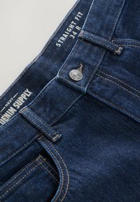 Proste niebieskie dżinsy w ciemnym odcieniu z zapięciem na guzik, widocznymi detalami szwów oraz metkami wskazującymi rozmiar 34 R i nazwę marki.