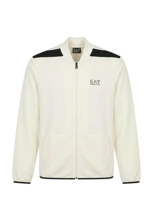 Giacca bianca con zip, strisce nere sulle spalle, polsini elasticizzati, tasche frontali e logo EA7 Emporio Armani sul petto.