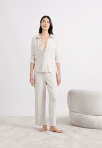 Világosszürke, puha anyagból készült kényelmes öltözet, mely gombos, hosszú ujjú felsőből és bő szárú nadrágból áll. Egyszerű és lazább kialakítás.