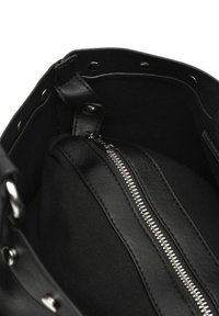 Wnętrze torby wykonane z czarnej skóry i materiału, z srebrnym zamkiem błyskawicznym oraz metalowymi zatrzaskami wzdłuż krawędzi otwarcia.