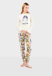 Lichtcrème lange mouwen overhemd met een graphic design; patroon pyjamabroek met kleurrijke bloem- en palmboommotieven.