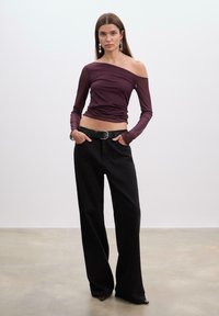 Bordeaux off-shoulder top, tætsiddende med lange ærmer; parret med højtaljede sorte brede bukser og et sort bælte med en sølvspænde.