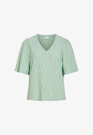 Lysegrøn bluse med korte ærmer, V-hals og subtilt geometrisk teksturmønster, løstsiddende pasform og let puffede ærmer.