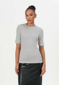 Gestreepte top met korte mouwen in wit en marineblauw, met een ronde halslijn en een aansluitende silhoeet, gecombineerd met een zwarte leren rok.