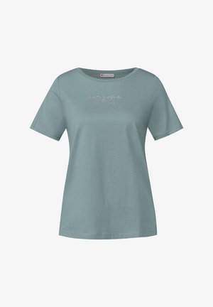 T-shirt en coton bleu clair à manches courtes, col rond, avec un design en texte script métallique sur la poitrine. Texture lisse, coupe décontractée.